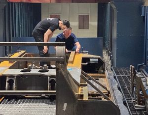 Michael von Briel steht mit einem Arbeiter an einer Fräsmaschine und erklärt ein neues Vorgehen.